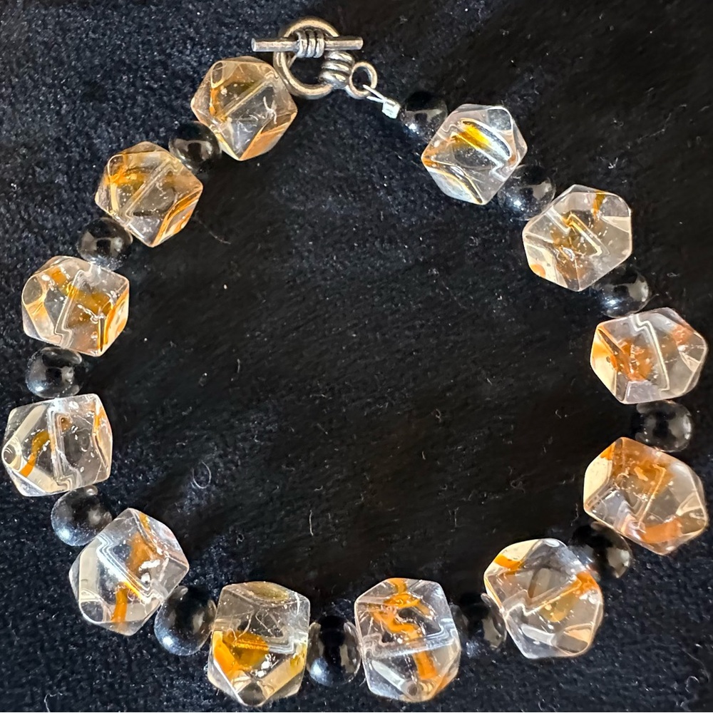 Clear beaded stretch women’s bracelet with orange and black speckles.